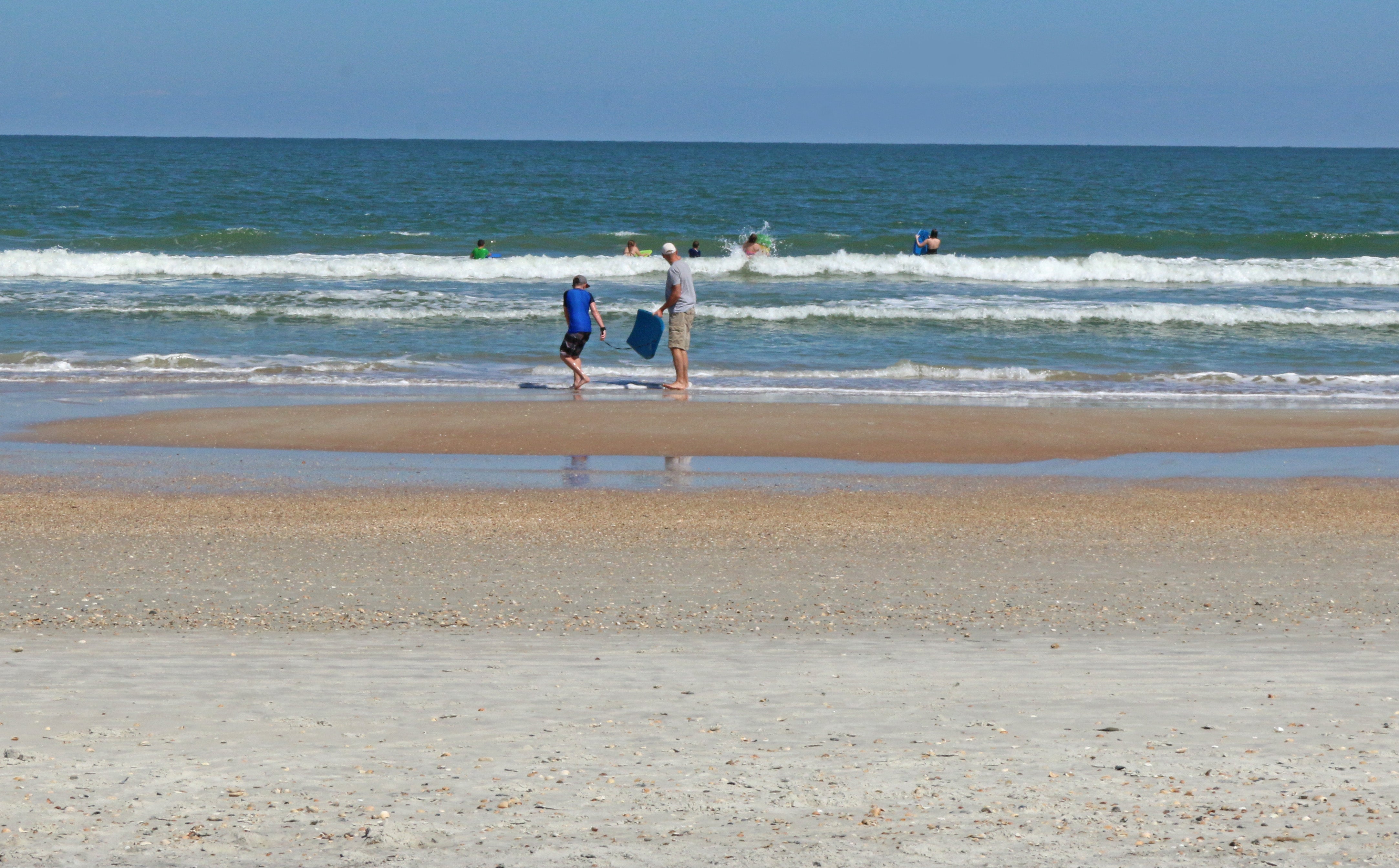 People standing in the waves at the beach